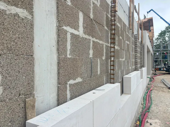 Blocs de chanvre montés entre poteaux béton sur la façade d’un bâtiment